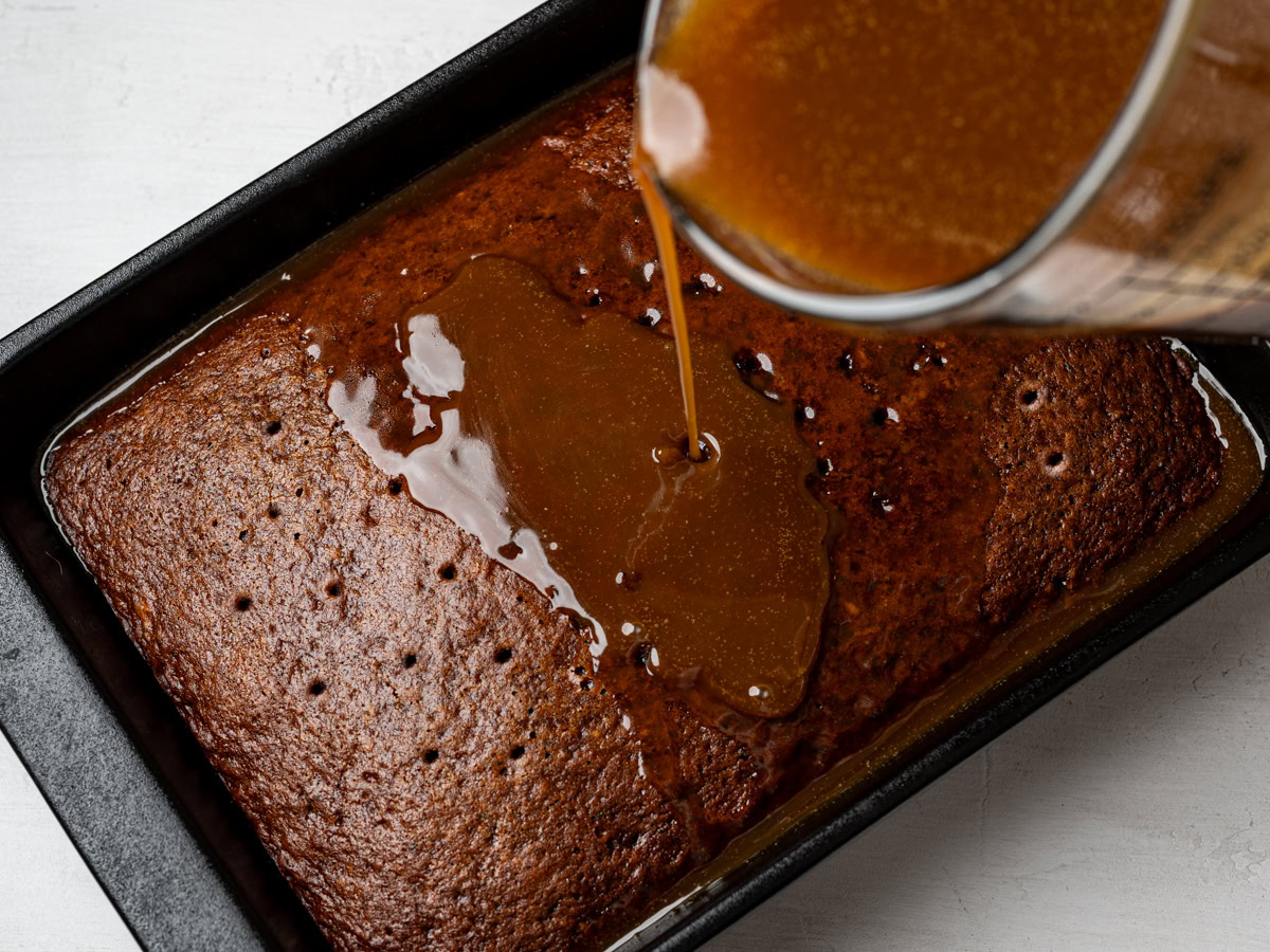 pouring toffee sauce over baked cake in baking dish