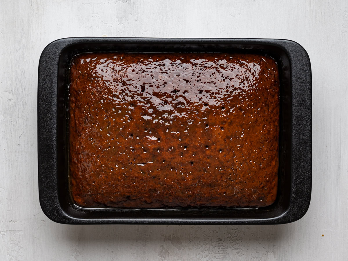 baked sticky toffee cake in baking dish with toffee sauce