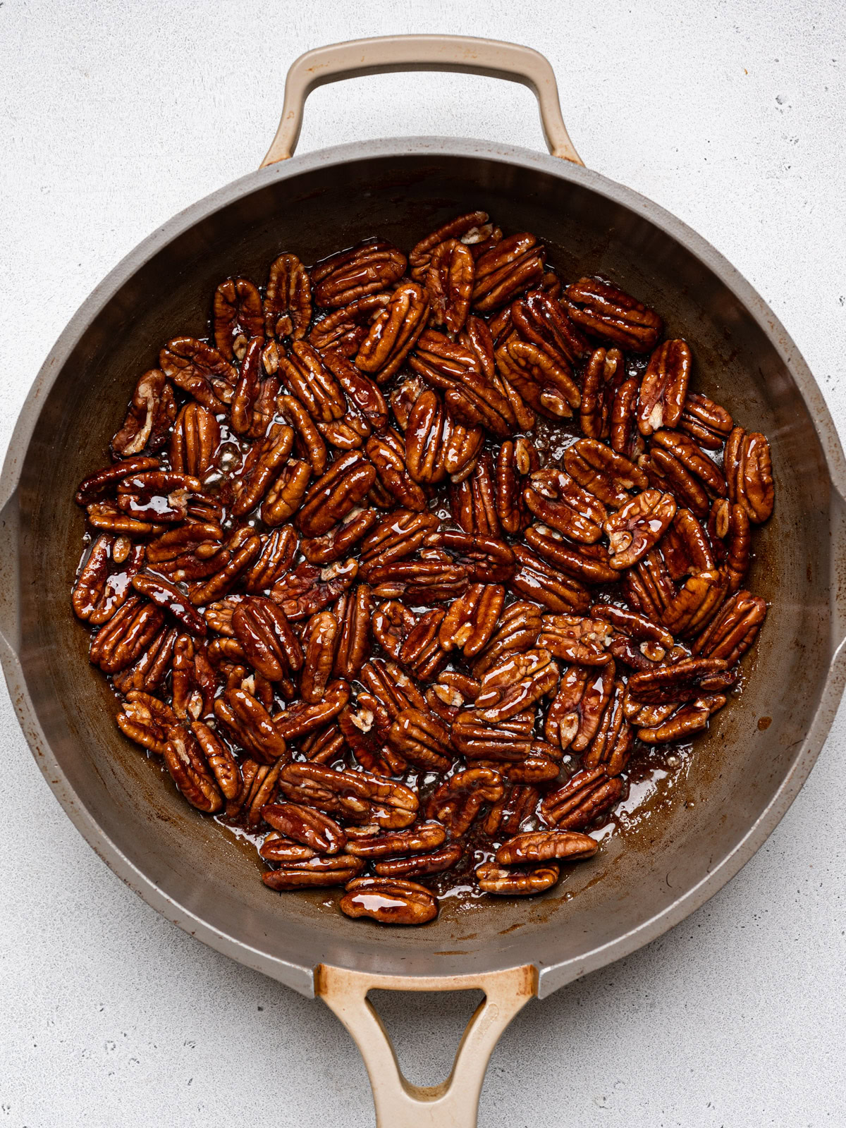 pecans cooking in skillet with sugar mixture 