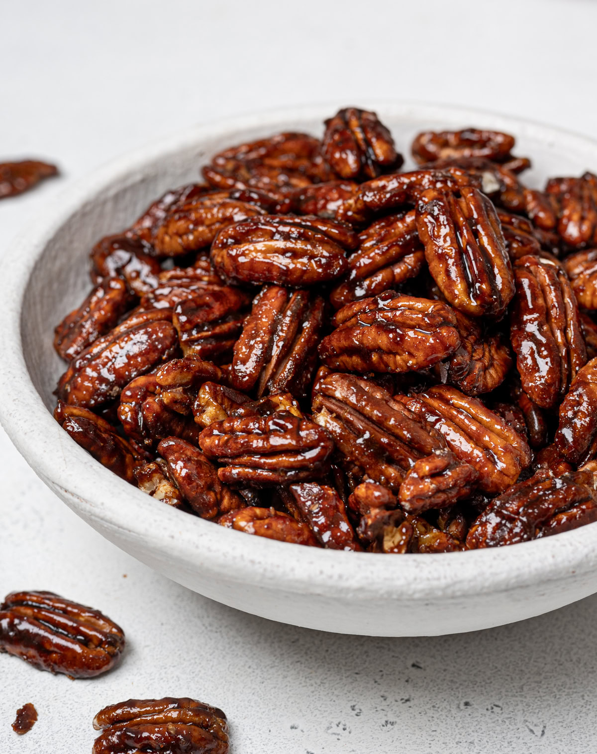 side view of candied pecans in white bowl