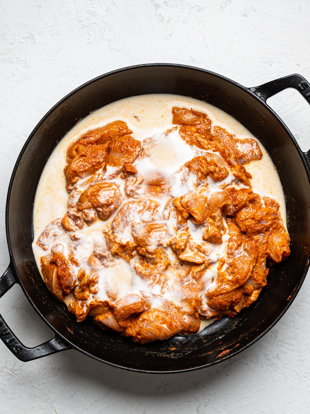 chicken coated with curry paste and coconut milk in skillet