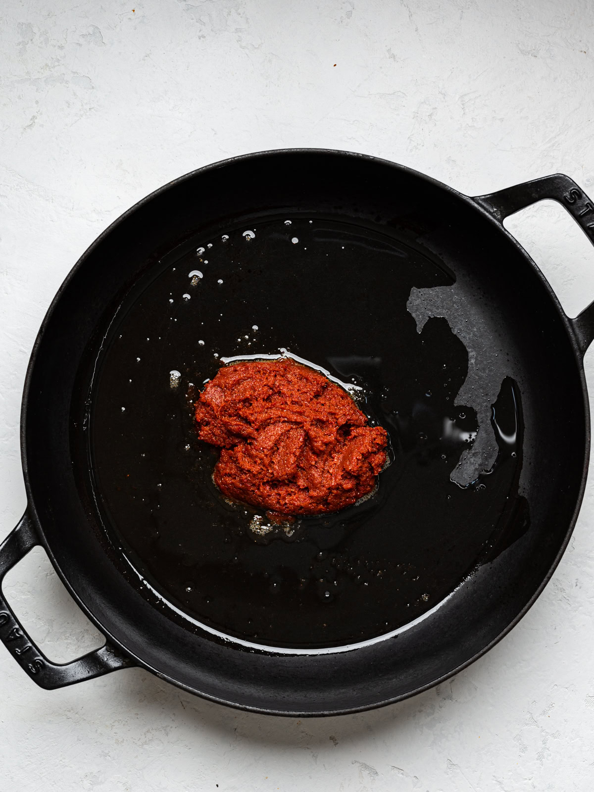 cooking curry paste with oil in black skillet