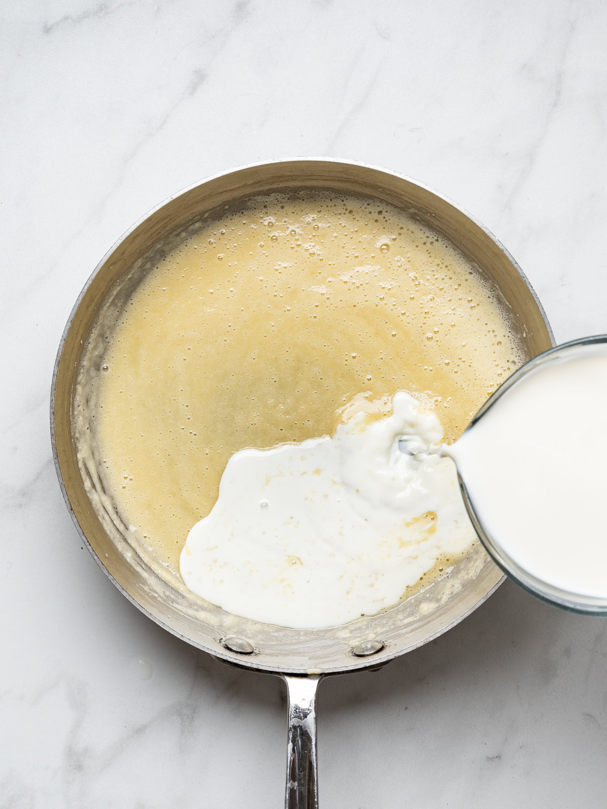 drizzling milk into butter and flor mixture to make bechamel sauce