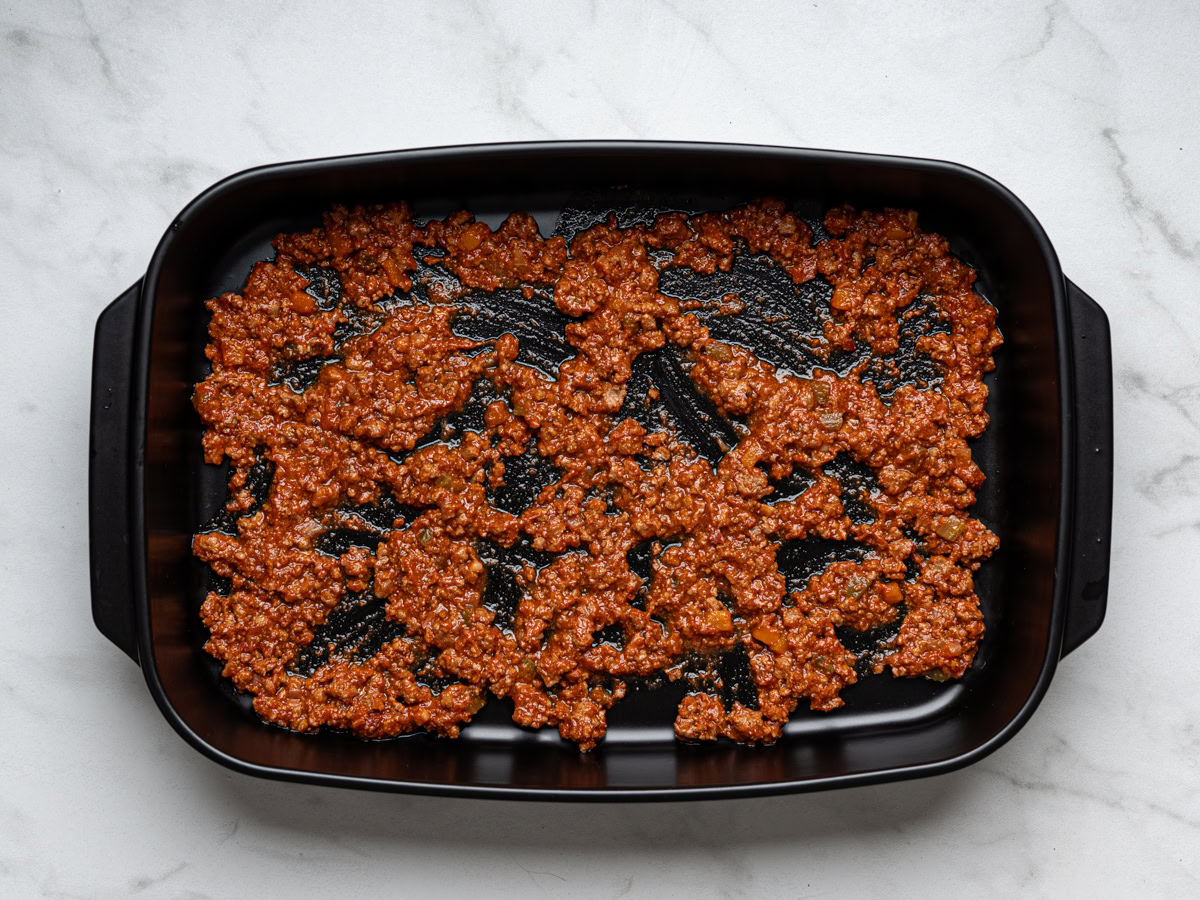 thin layer of bolognese sauce on bottom of lasagna baking dish