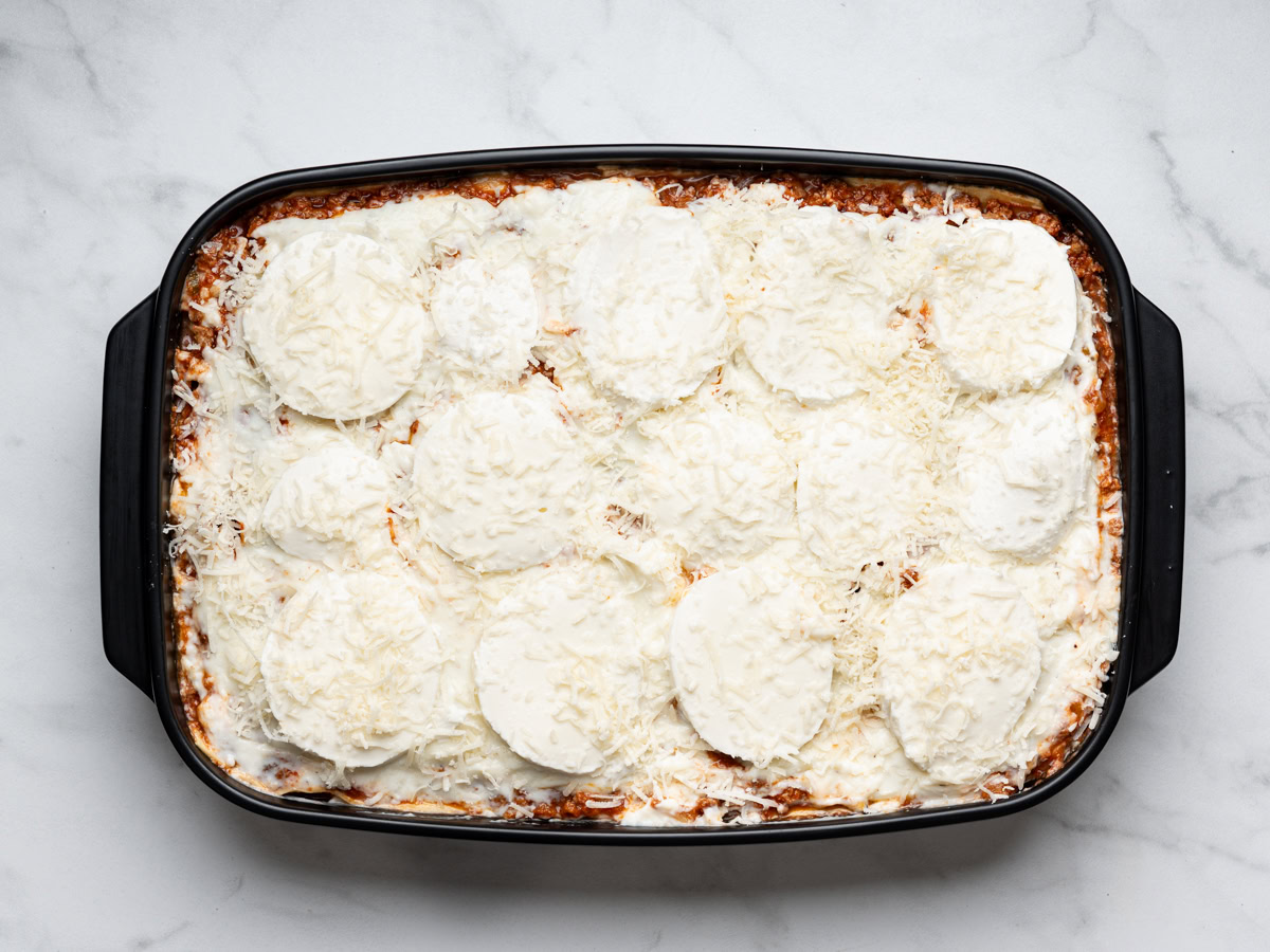 assembled lasagna topped with fresh mozzarella slices and parmesan