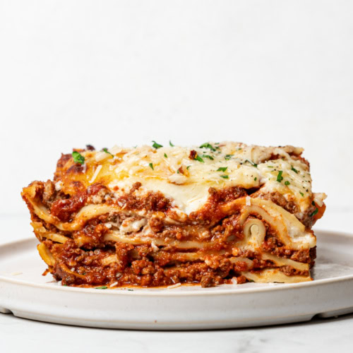 side view of a sliced serving of lasagna al forno on small white plate