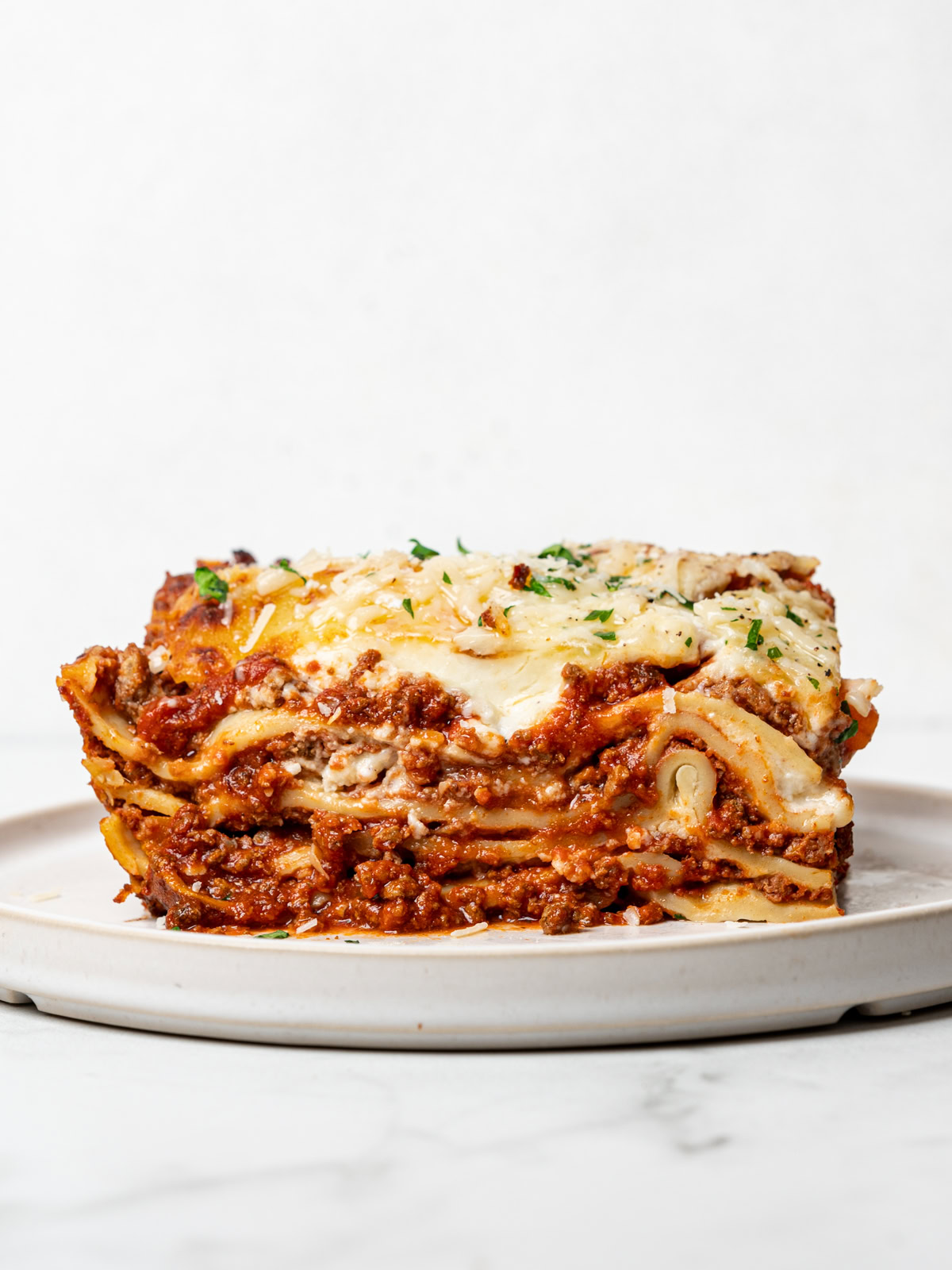 side view of a sliced serving of lasagna al forno on small white plate