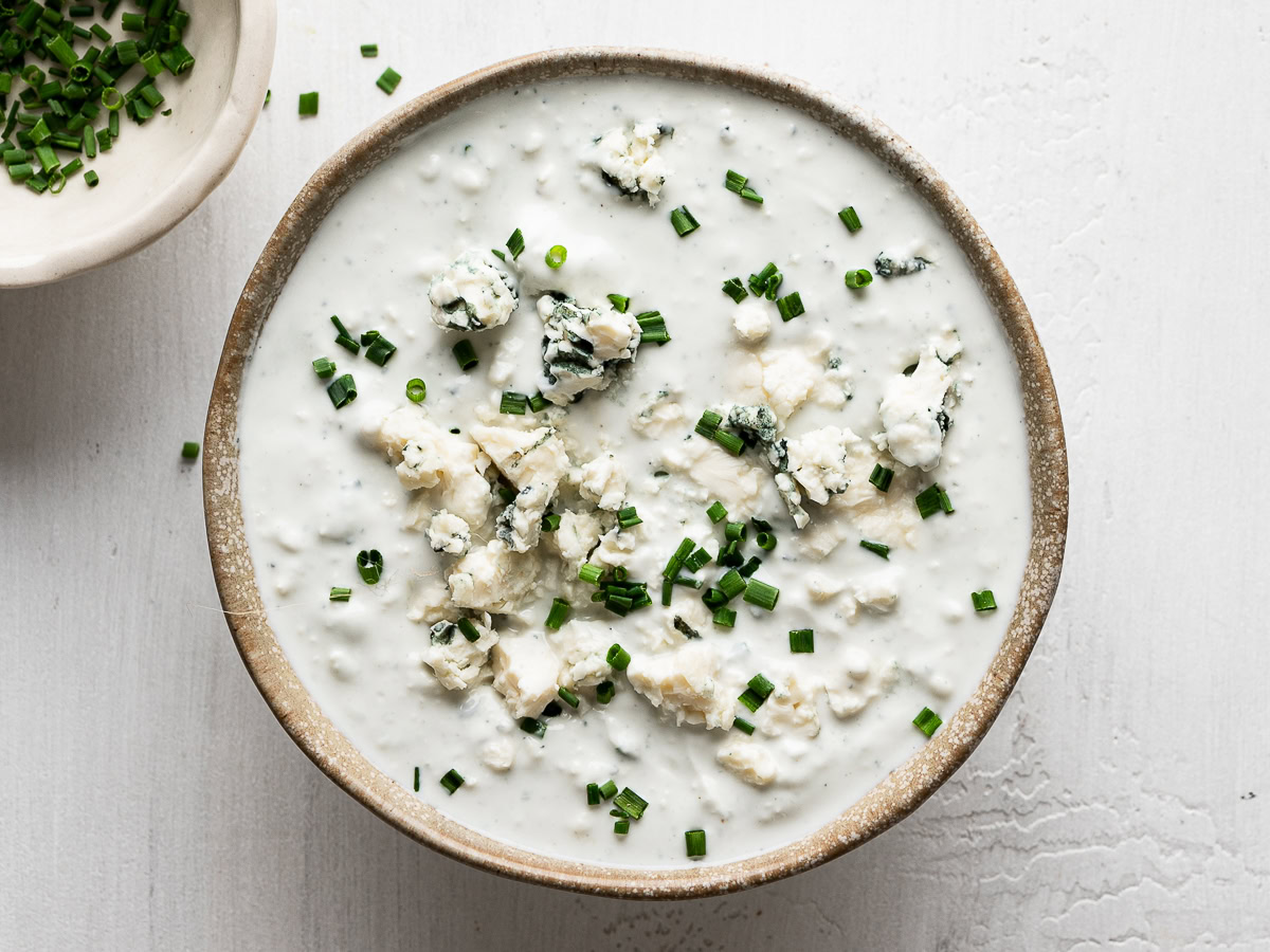 blue cheese dip served in small round bowl and a small bowl with chopped chives on the side