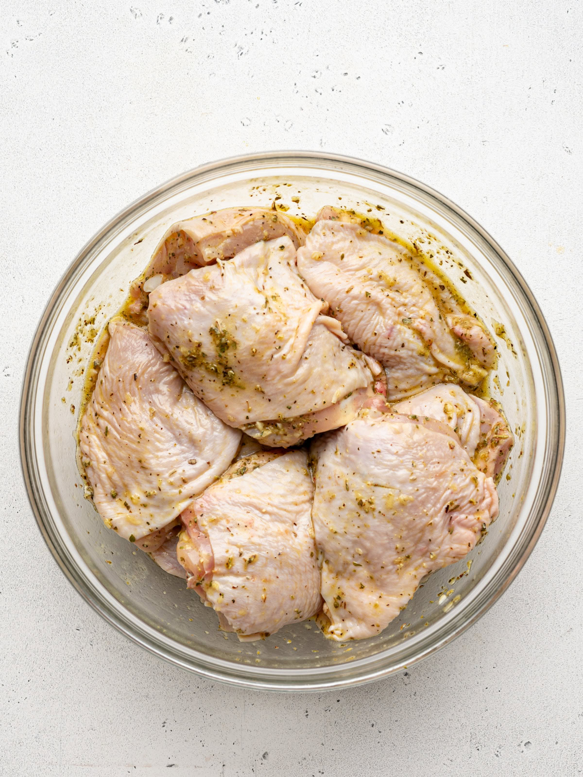 chicken thighs marinating in large glass bowl