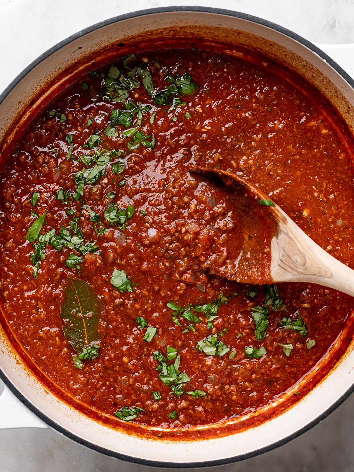 closeup of cooked spaghetti sauce in pot with chopped basil