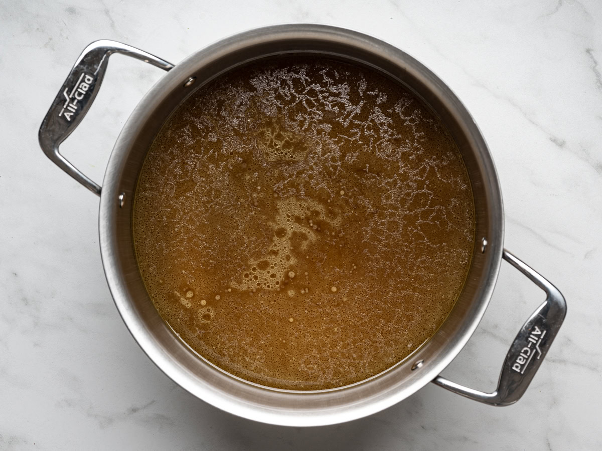 strained slow cooker bone broth in a large stainless steel pot