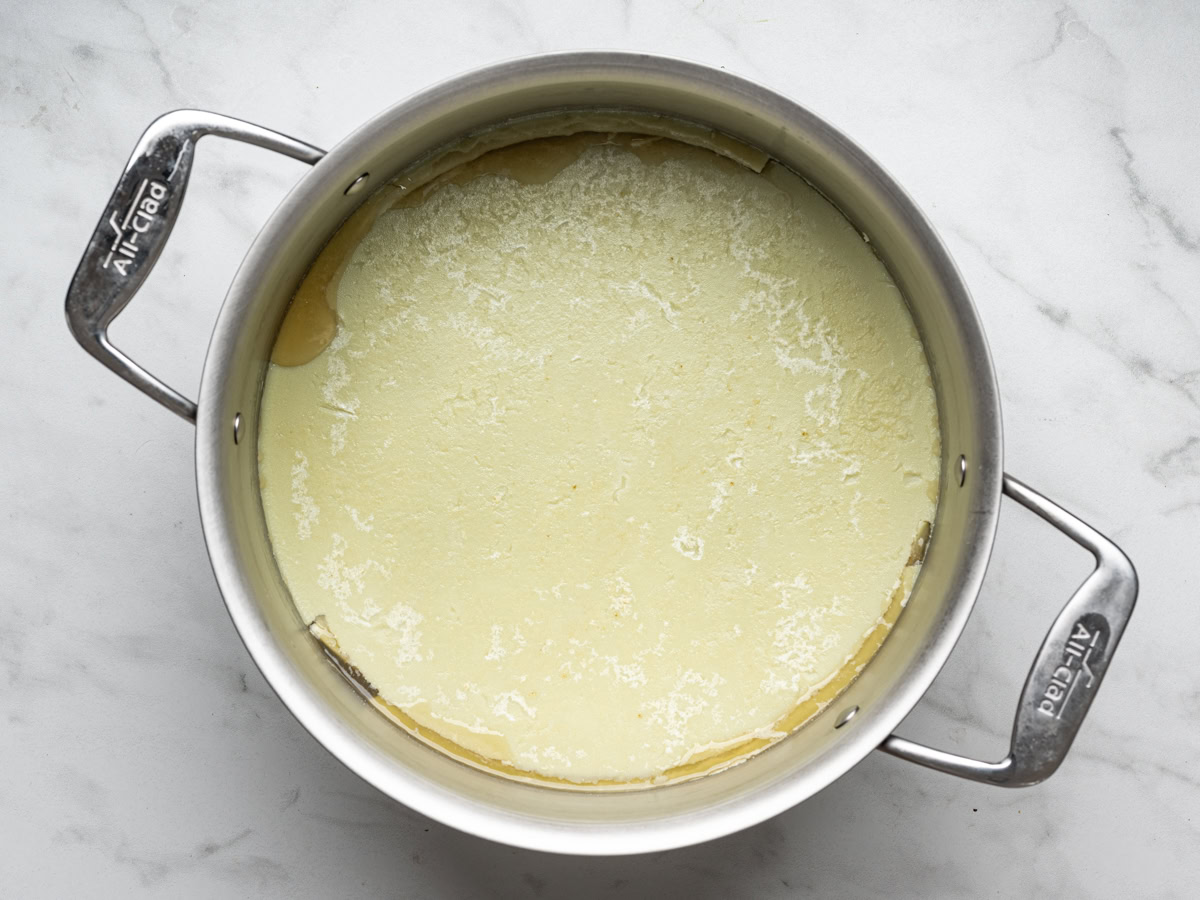 broth in a large stainless steel pot with congealed layer of fat on top