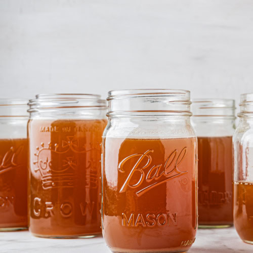 closeup of five mason jars filled with slow cooker bone broth