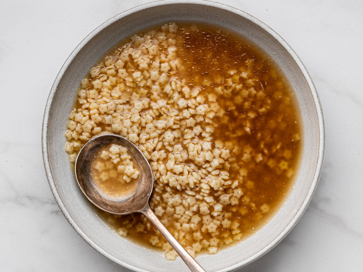 Top view of Pastina soup served in a bowl with a spoon