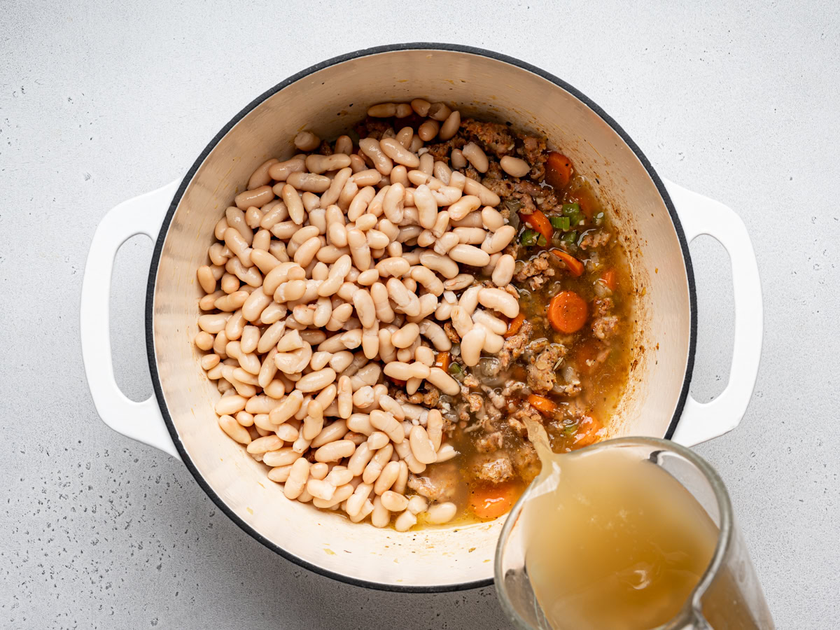 beans added to the pot and broth being poured into the soup pot