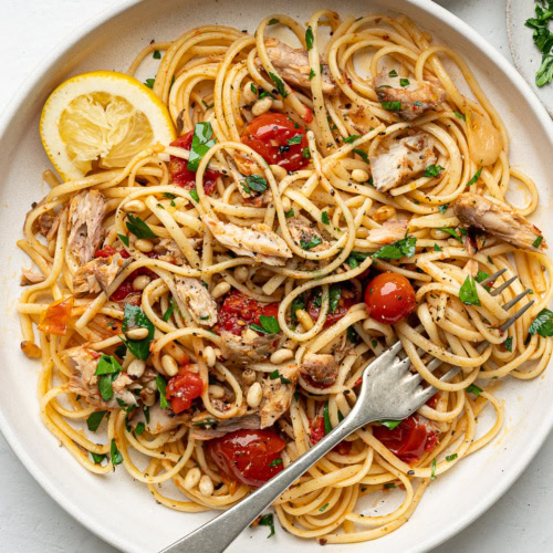 canned mackerel pasta served on white plate with twirled spaghetti on a fork