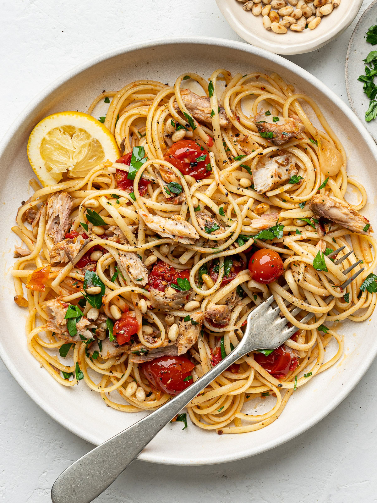 canned mackerel pasta served on white plate with twirled spaghetti on a fork