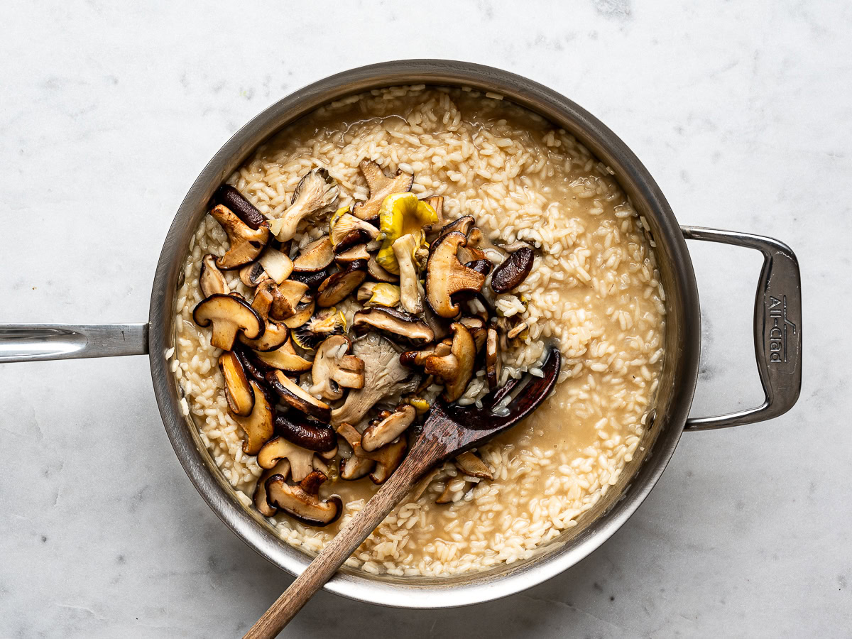 sautéed mushrooms added back into the risotto mixture that is in a stainless steel pan