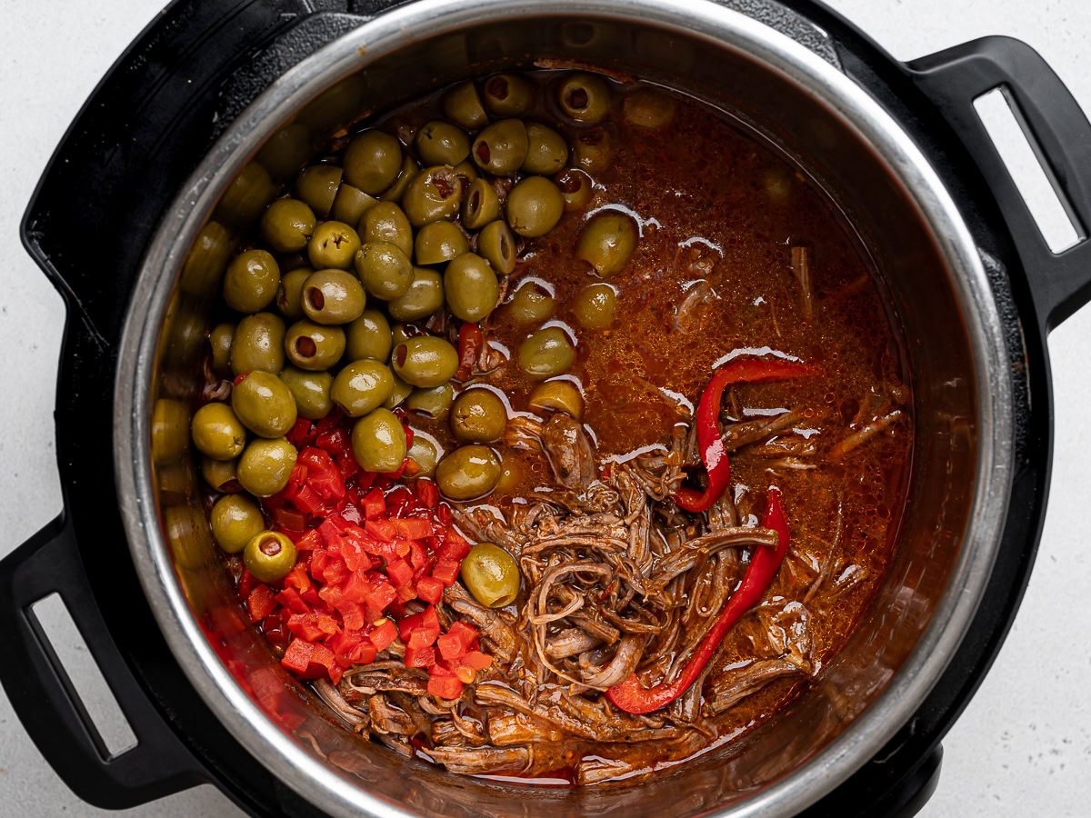 shredded beef back in instant pot with olives and pimentos added to the mixture