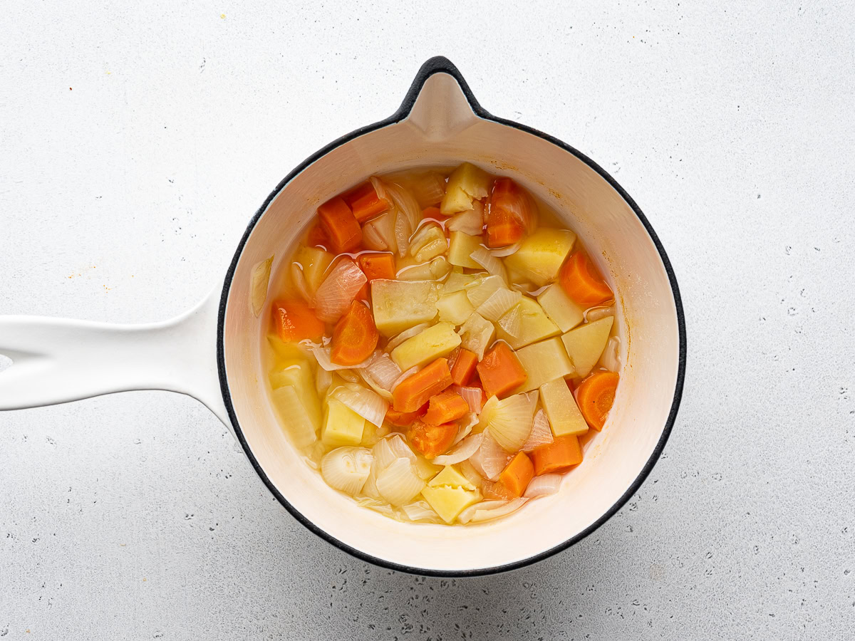 boiled potatoes, carrots, and onion in medium-sized white saucepan