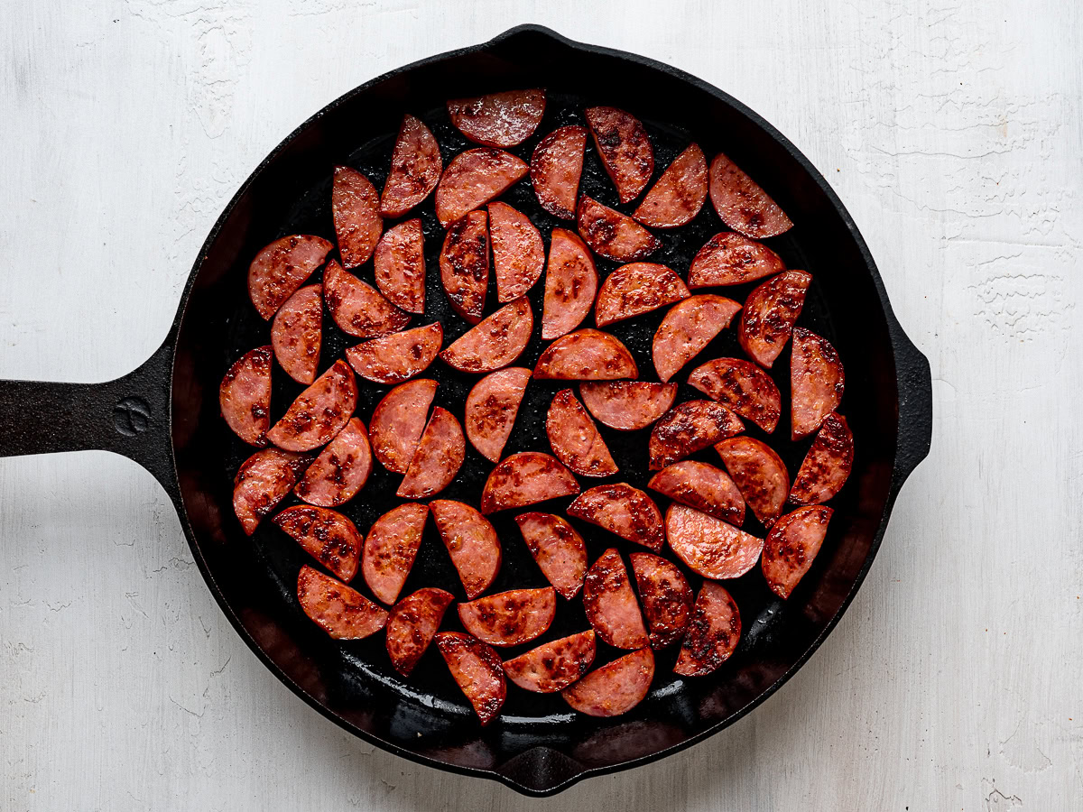 Sliced kielbassa sausage browned in black skillet.