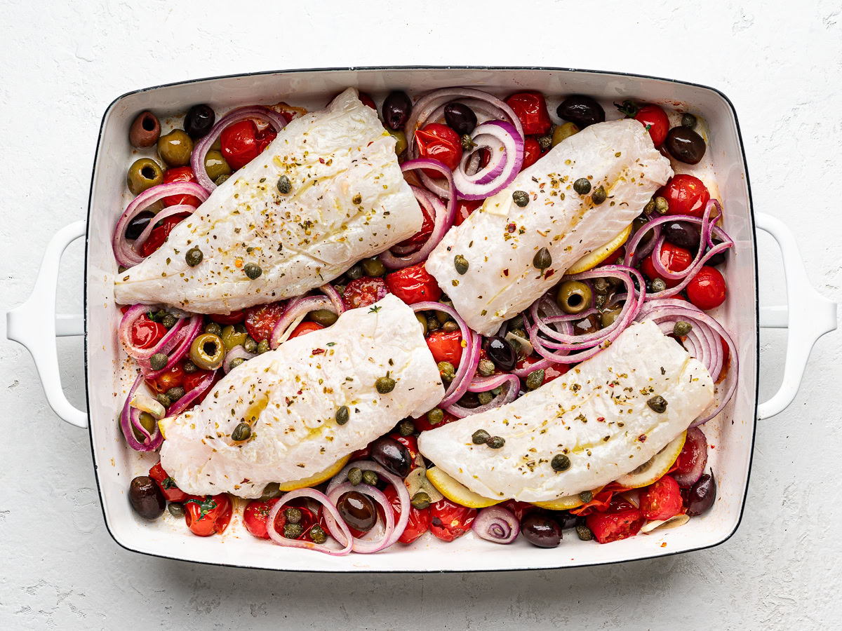  4 raw cod fillets placed on top of baked cherry tomato mixture. 