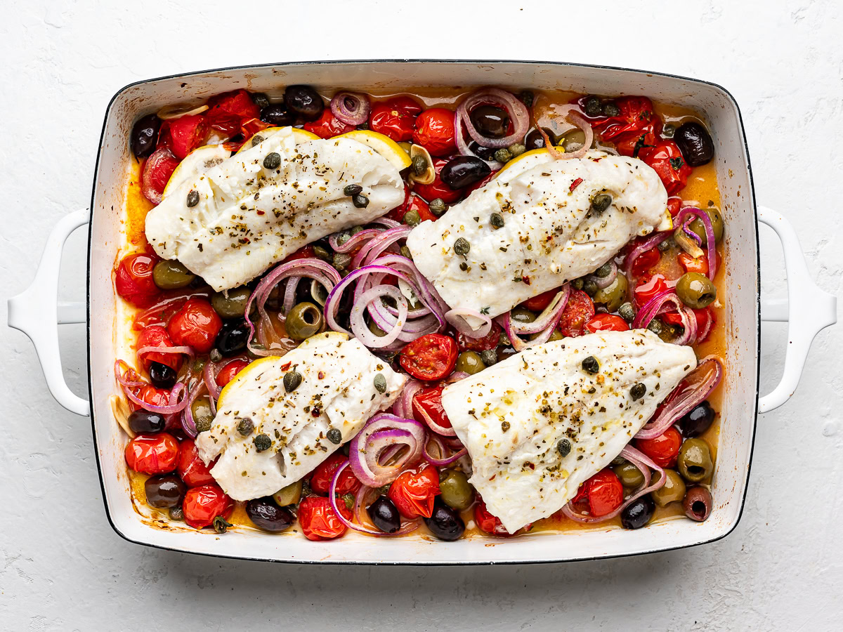 Baked cod fillets with cherry tomato mixture in baking dish.