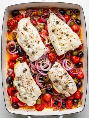 4 cod fillets on top of a burst cherry tomato sauce in a baking dish.