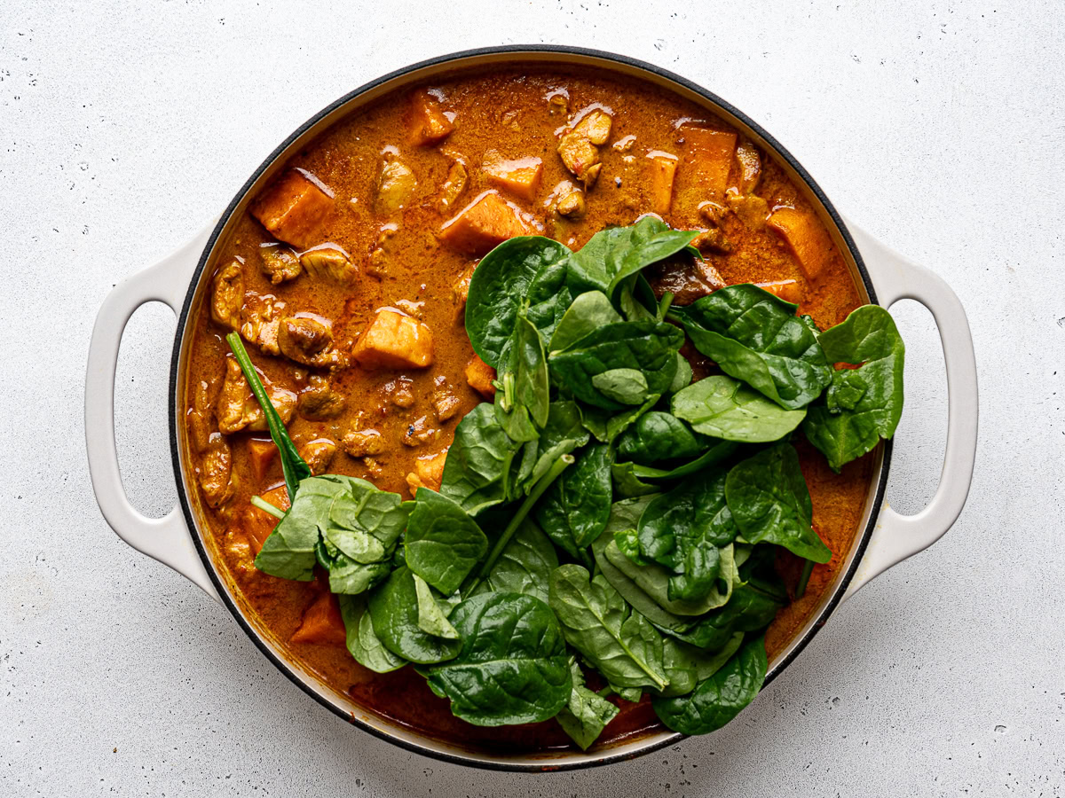 Adding baby spinach to the chicken sweet potato curry.