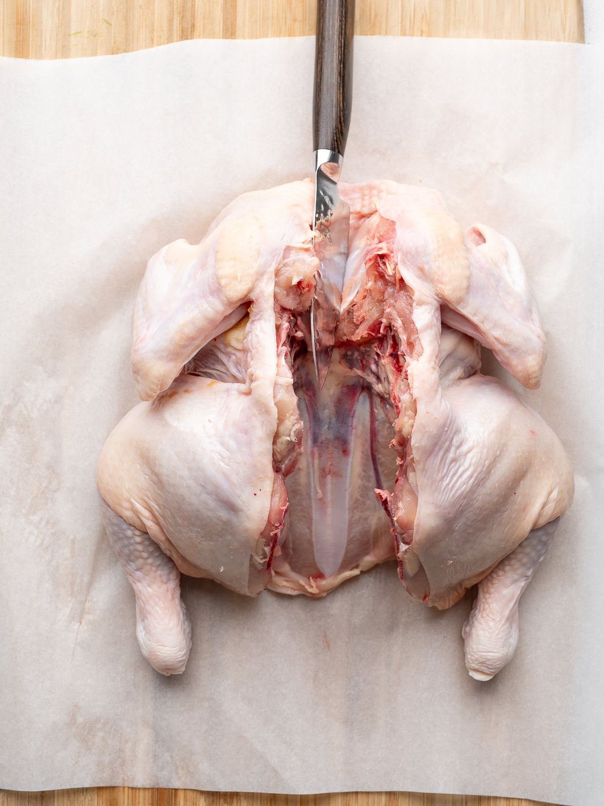 Using a small sharp knife to cut into the sternum of the chicken.