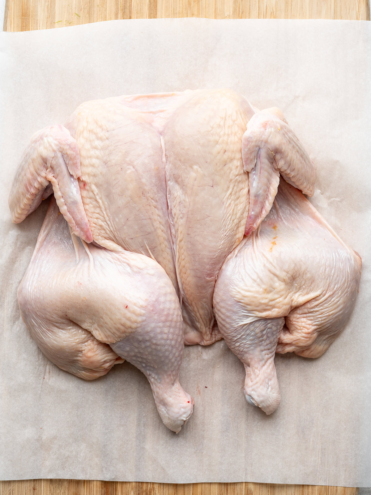 Top side of spatchcocked chicken on cutting board.