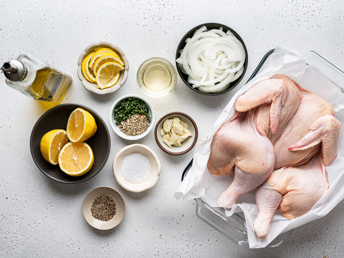 The raw spatchcocked chicken with the rest of the recipe ingredients prepared in small bowls. 