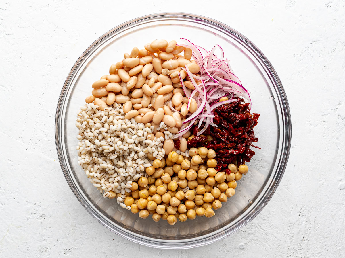 ingredients for bean salad in a glass mixing bowl. 