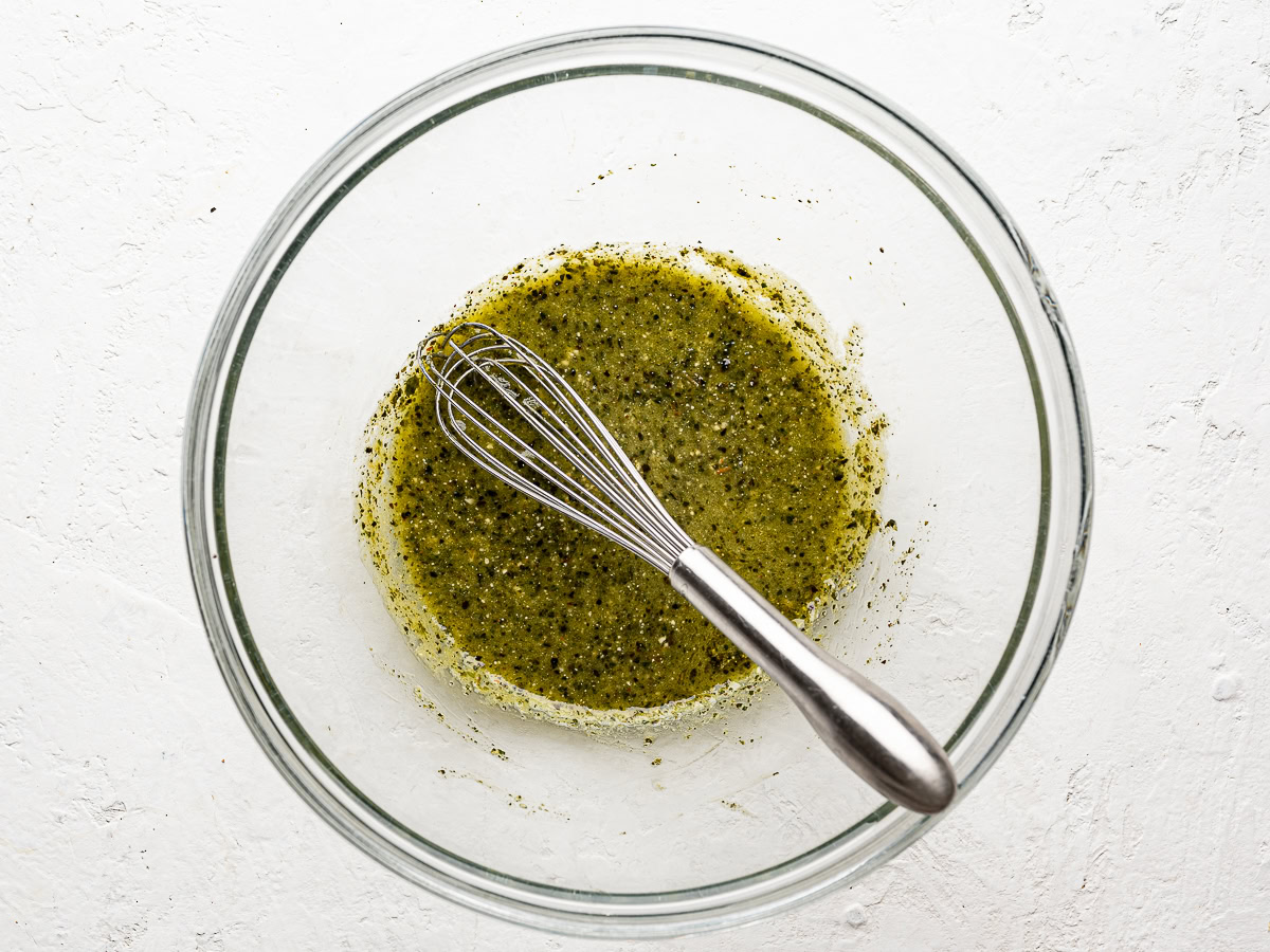 pesto dressing mixed in large glass mixing bowl.