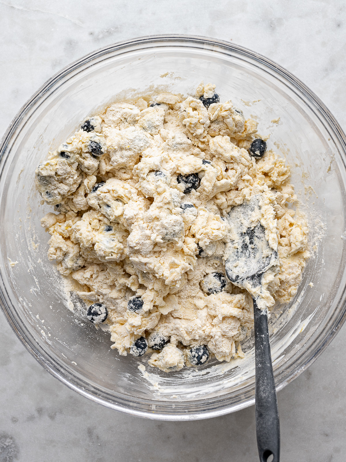 Combining dough in glass bowl with a silicone spatula.