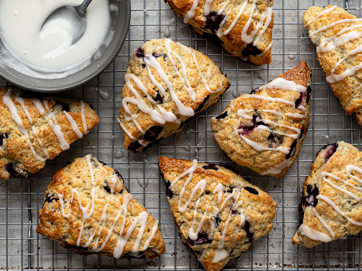 Baked scones drizzled with glaze on baking sheet rack.