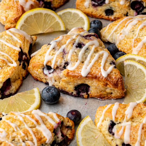Side-view of lemon blueberry scones with lemon glaze drizzled over the top.
