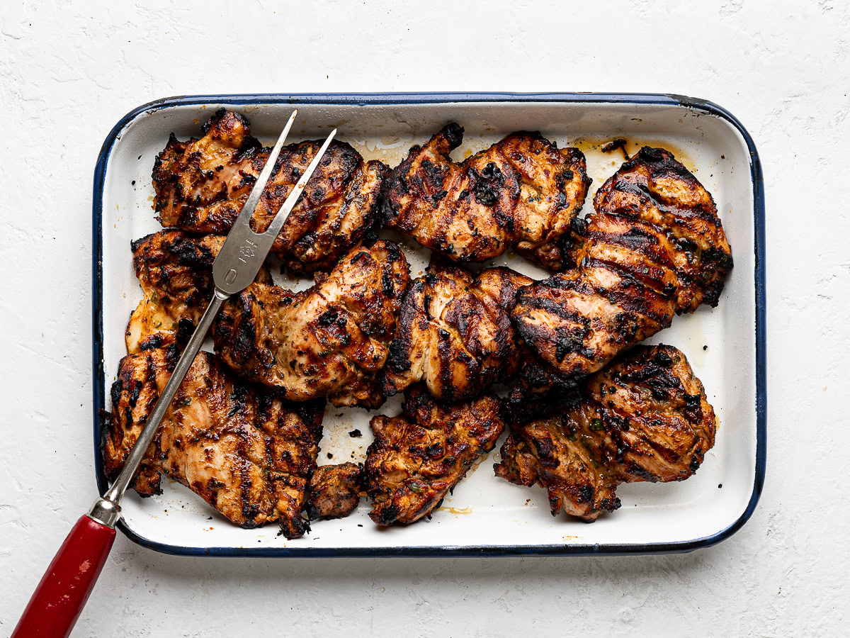 Grilled chicken thighs on a tray with bbq fork.