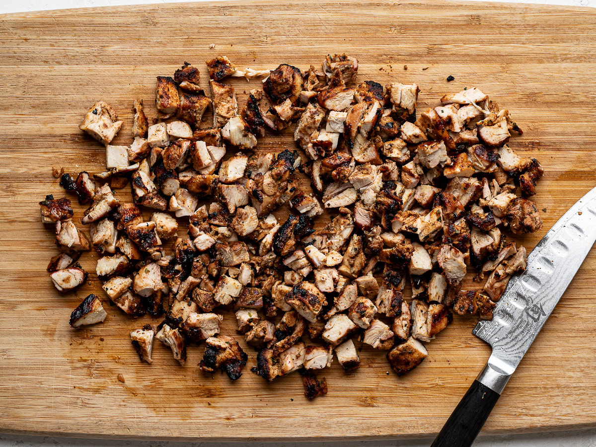 Chopped grilled chicken on wood cutting board. 