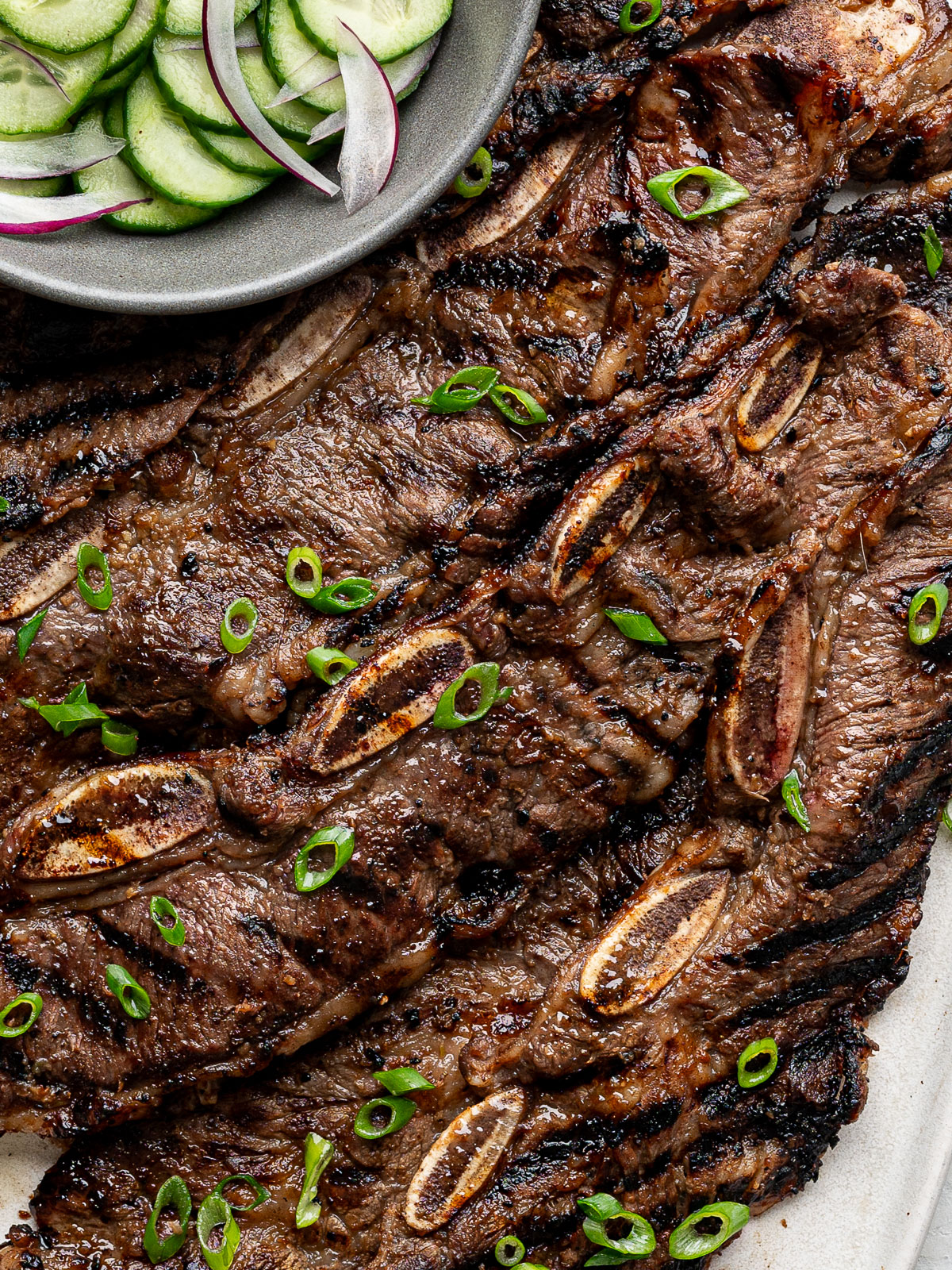Close up of Grilled Korean-Style Short Ribs (Galbi) on a white rectangular platter.