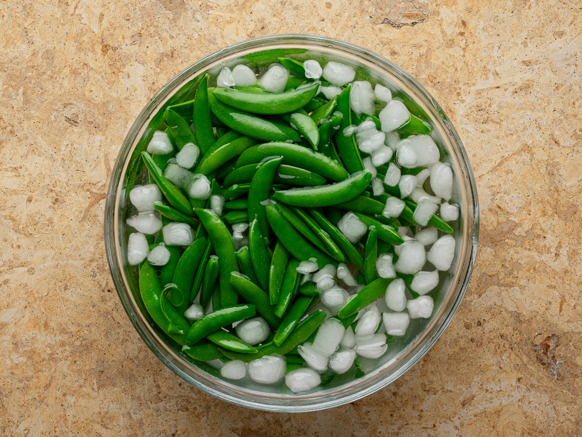 Sugar snap peas in a bowl of ice water.