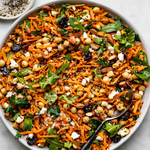 Carrot Salad with crispy quinoa served on a large round platter with small salt and pepper pinch dish on the side.