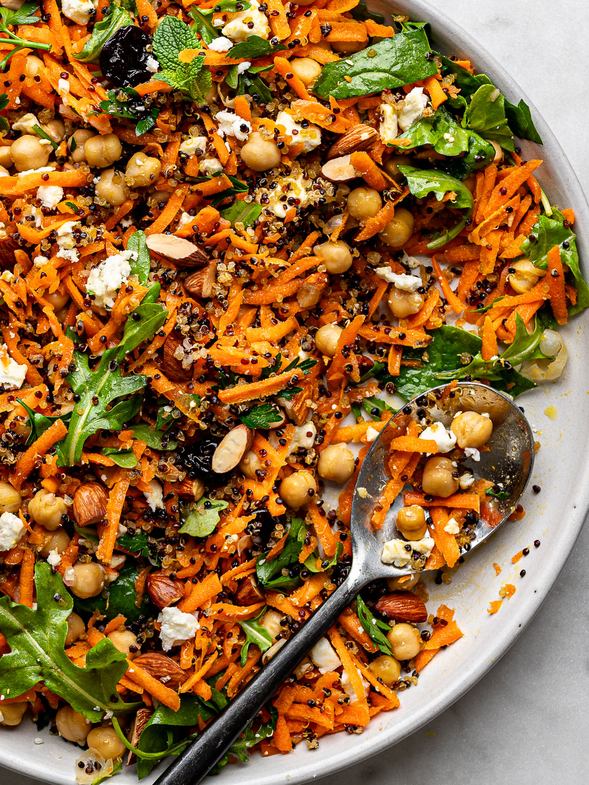 Close up of Carrot Salad with crispy quinoa served on a large round platter with serving spoon.