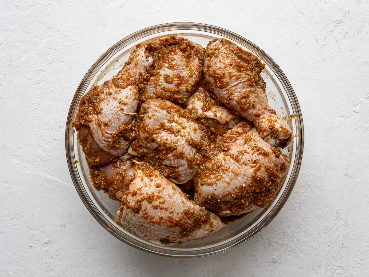 Chicken pieces marinating in glass bowl. 