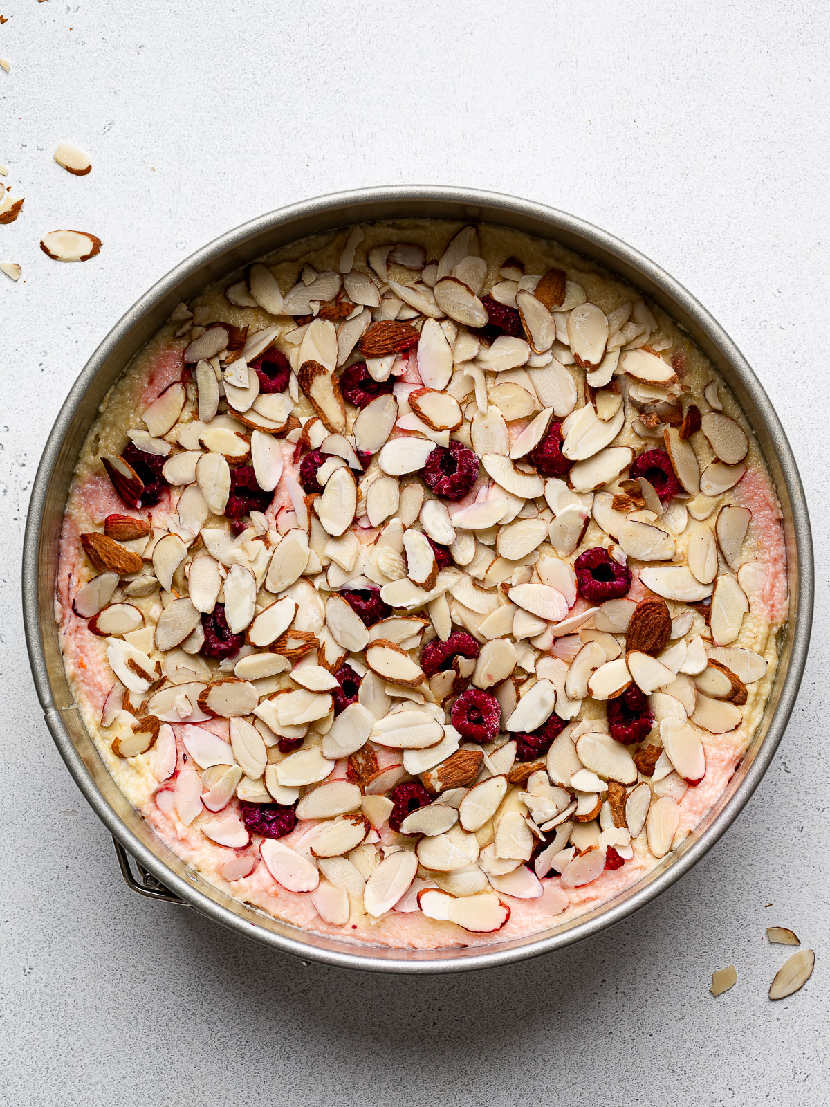 Flaked almonds scattered over top of cake batter in pan.
