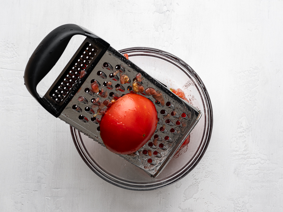 Grating a whole tomato with a box grater. 