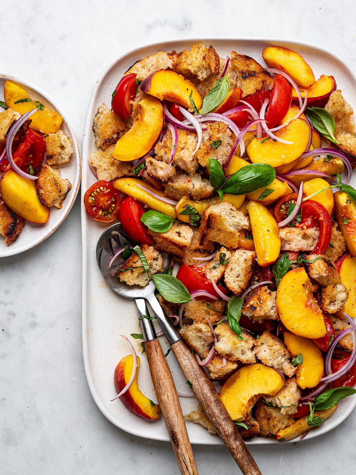 Peach panzanella salad platter with small plate of salad on the side. 