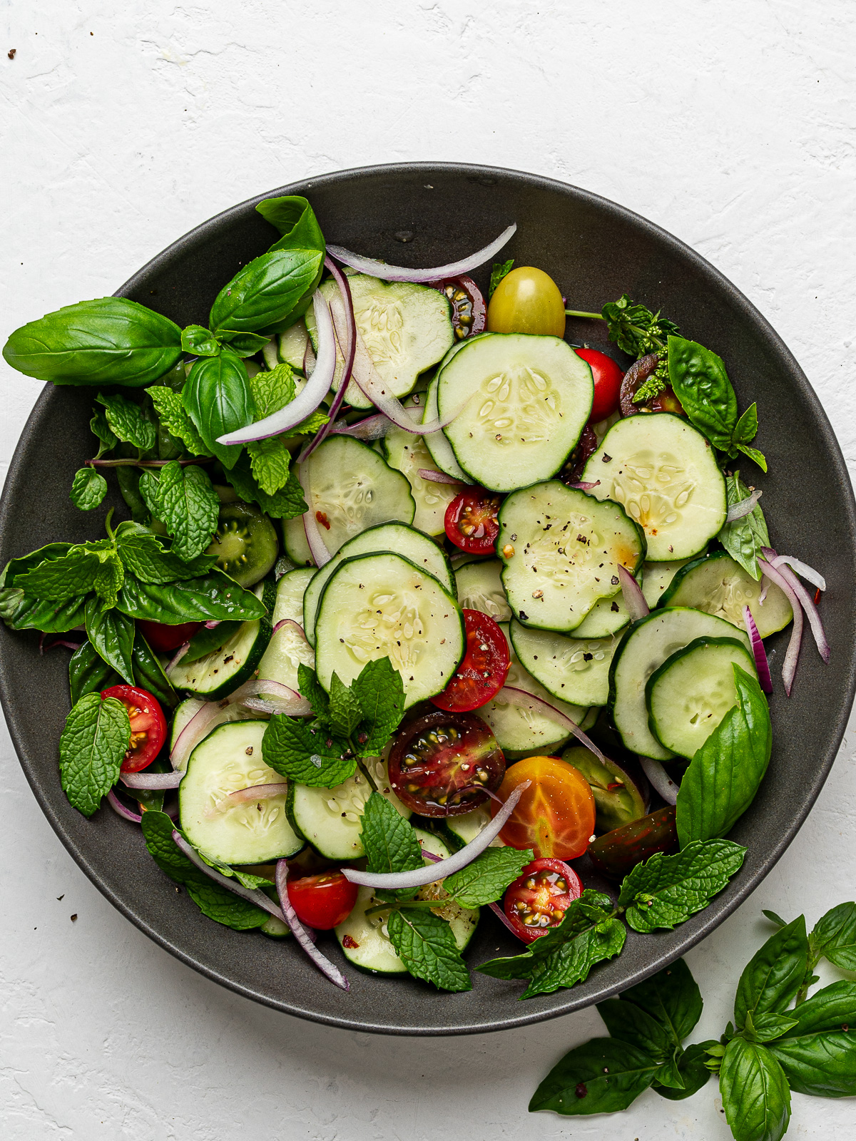 Cucumber salad prepared with dressing in a tray bowl.