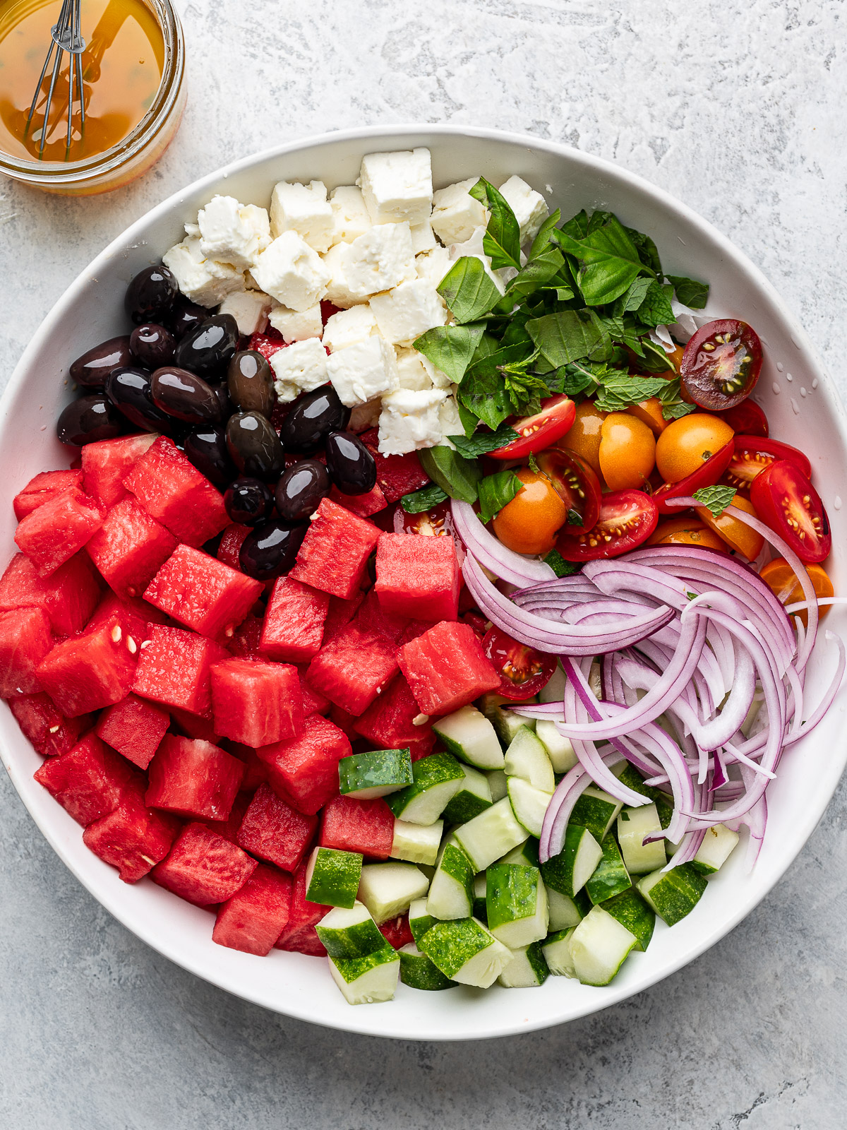 Salad ingredients arranged in white bowl.