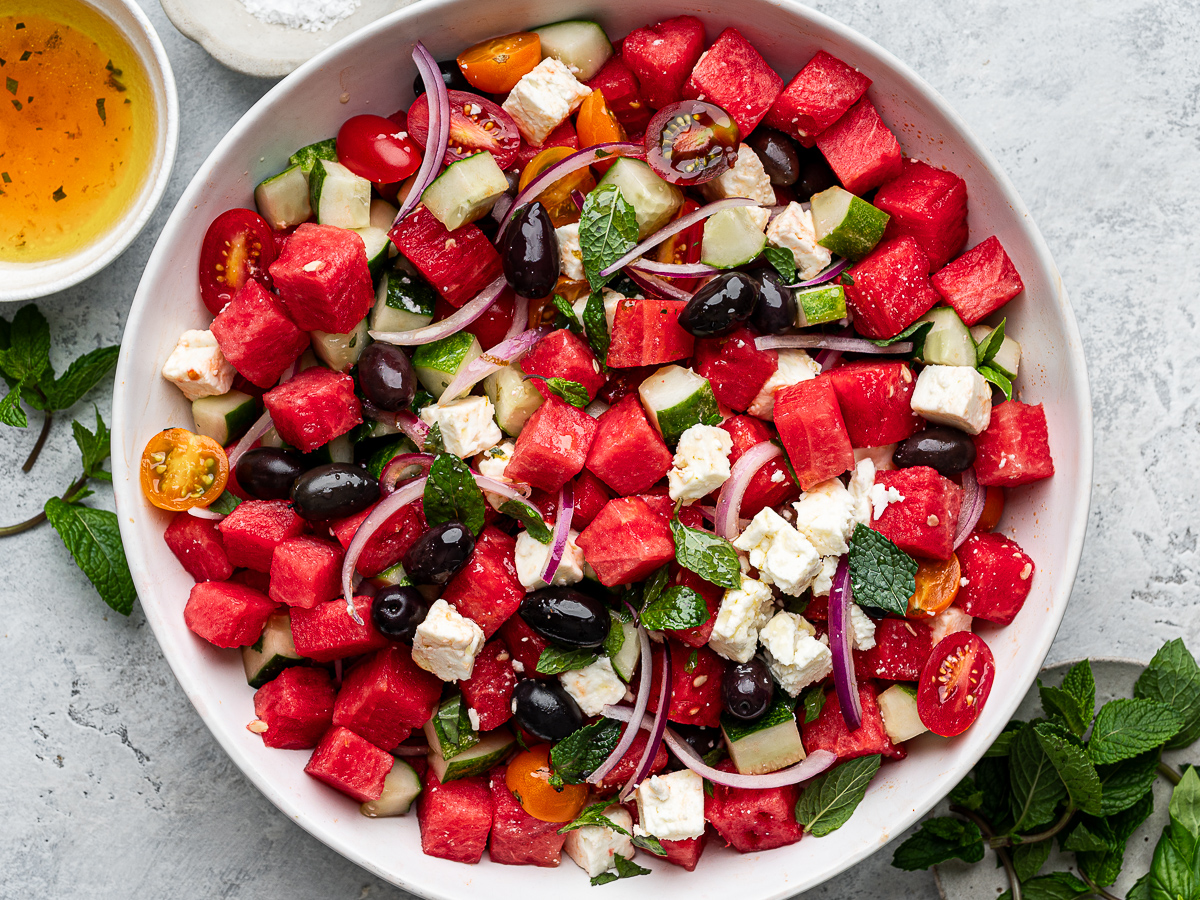 Watermelon salad prepared in bowl with dressing on the side.